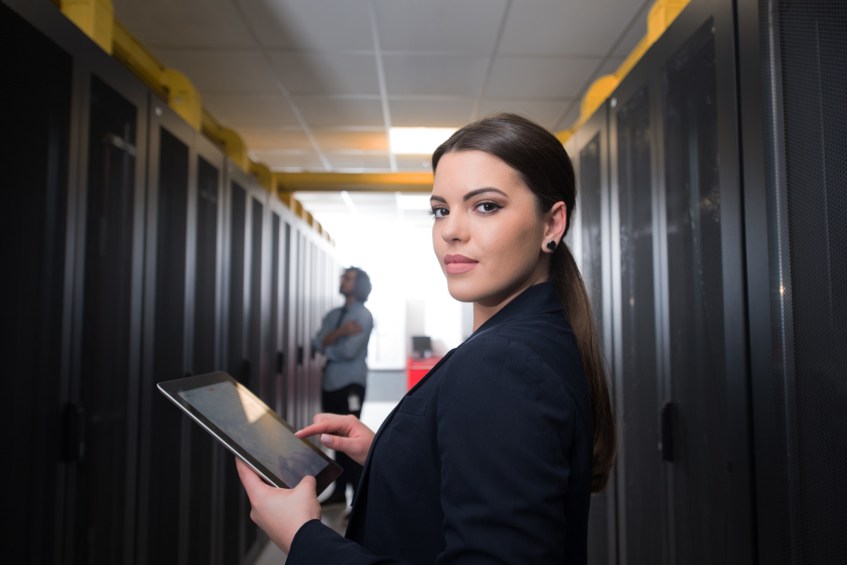 A woman holding a tablet in a server room