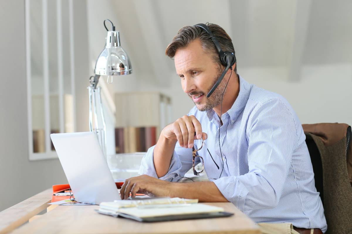Businessman working remotely on his laptop and using a headset