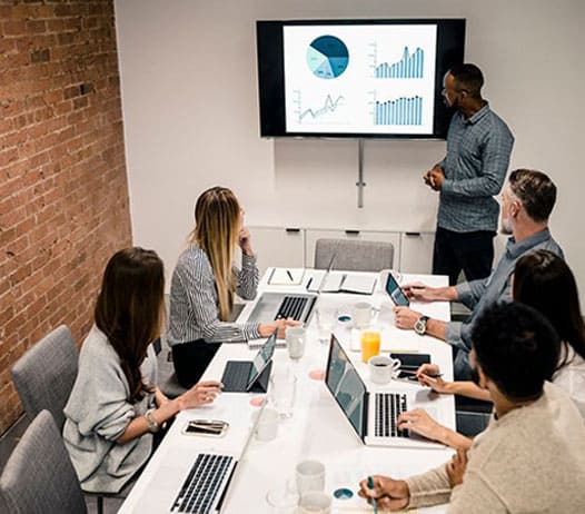 Business People in a Meeting Looking Towards Monitor in Front of Room