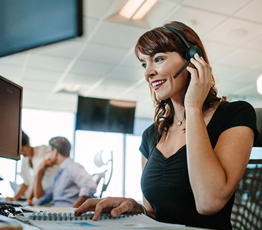 Simling Woman Wearing Headset at Desk